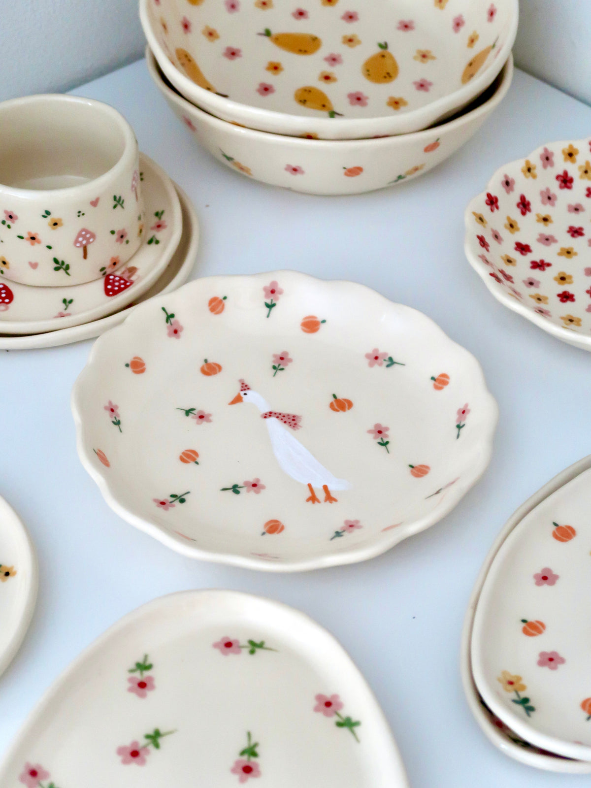 Scalloped plate with a duck, pumpkins, and pink flowers