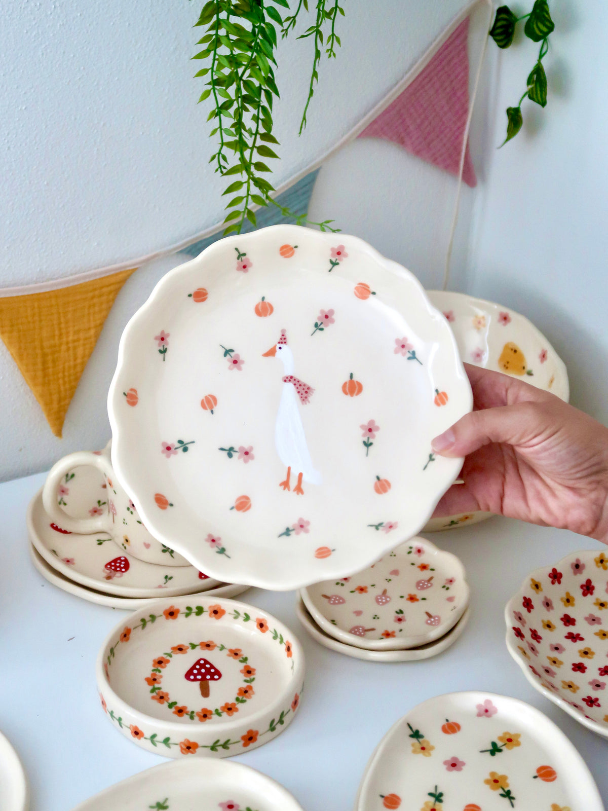 Scalloped plate with a duck, pumpkins, and pink flowers