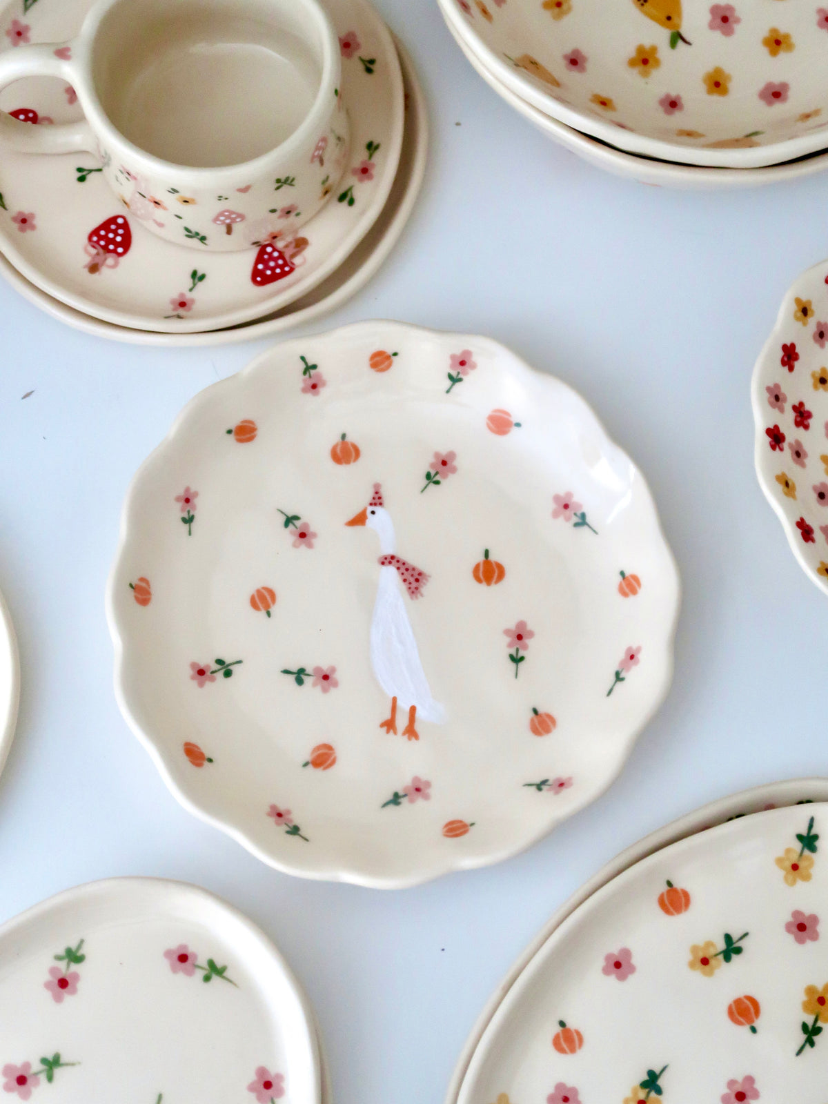 Scalloped plate with a duck, pumpkins, and pink flowers